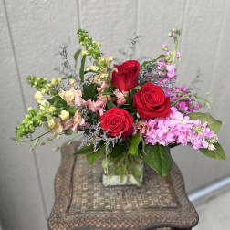Bouquet of red roses and pink flowers in a clear glass vase