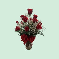 Red roses in a glass vase with baby's breath and a red ribbon