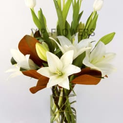 White lilies and tulips in a clear glass vase