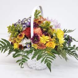 Mixed flower basket with a white handle and colorful blooms