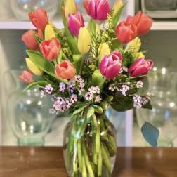 Mixed tulips in pink, coral, and yellow arranged in a glass vase