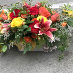 Low floral arrangement with roses and lilies in a rectangular container