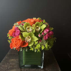 Orange roses and green orchids in a square glass vase