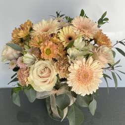Peach and cream bouquet with roses, gerbera daisies, and chrysanthemums in a glass vase