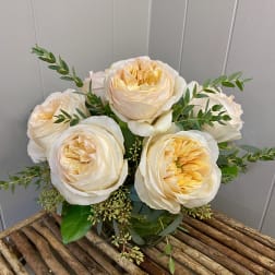 Bouquet of cream and pale peach roses with greenery in a glass vase