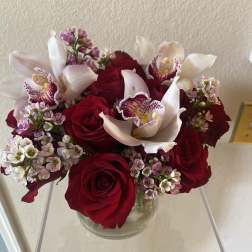Red roses with white orchids in a clear glass vase