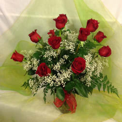 Bouquet of red roses with white filler flowers in a glass vase