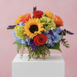 Colorful bouquet with sunflowers, roses, and hydrangeas in a glass vase