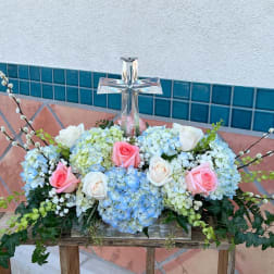 Floral arrangement with roses and hydrangeas around a clear glass cross