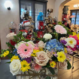 Mixed bouquet in a rustic wooden box with roses, gerbera daisies, hydrangea, and ranunculus