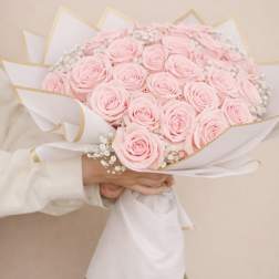 Bouquet of pale pink roses wrapped in white paper with gold trim