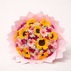 Bouquet of sunflowers, pink gerbera daisies, and roses wrapped in pink paper