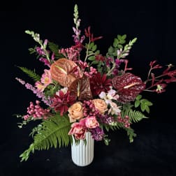 Mixed bouquet in a white vase with pink, burgundy, and peach blooms