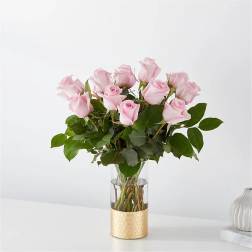Pink roses arranged in a clear glass vase with a gold base