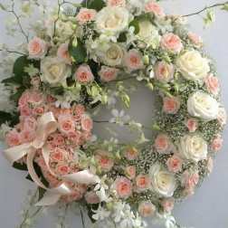 Heart-shaped floral wreath with pink and white roses and ribbon
