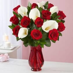 Red roses and white calla lilies in a red glass vase