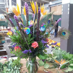 Tall tropical bouquet in a glass vase with roses and bird-of-paradise flowers