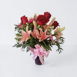 Bouquet of red roses and pink lilies in a vase with a pink polka-dot ribbon