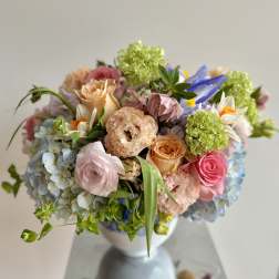 Pastel bouquet of roses, hydrangeas, and mixed blooms in a white vase