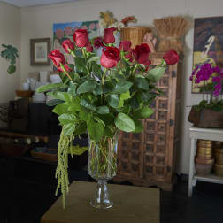 Tall vase arrangement of red roses with cascading greenery