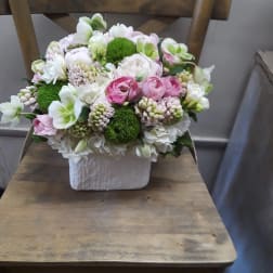 Pink and white floral arrangement in a white square vase