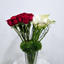Red and white roses in a clear glass vase with green moss