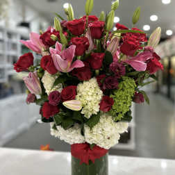 Bouquet of red roses, pink lilies, and white hydrangeas in a green vase