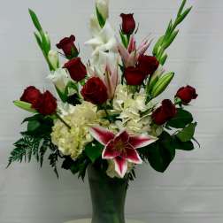 Tall floral arrangement with red roses, white lilies, and pink stargazer lilies in a vase