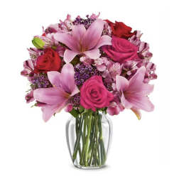 Pink lilies and roses arranged in a clear glass vase