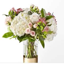 White hydrangeas and pale pink roses in a clear glass vase