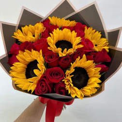 Bouquet of red roses and yellow sunflowers wrapped in dark paper