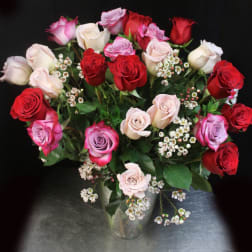Bouquet of red, pink, and white roses in a clear glass vase