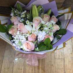 Bouquet of pale pink roses and white lilies with lavender wrapping