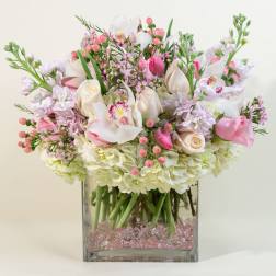 Pink and white floral arrangement in a square glass vase