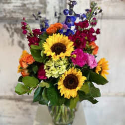 Mixed bouquet with sunflowers, roses, and colorful blooms in a glass vase