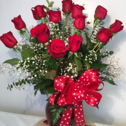 Bouquet of red roses in a vase with a heart-patterned ribbon