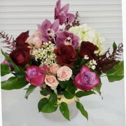 Bouquet of pink orchids, red and pink roses, and white hydrangea in a vase