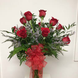 Red roses in a clear glass vase with a red ribbon bow