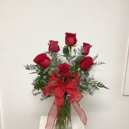 Red roses in a clear glass vase with a red ribbon bow