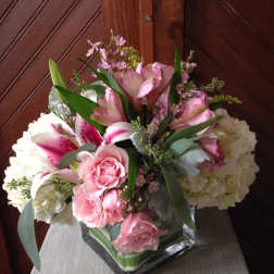 Pink and white floral arrangement in a square glass vase
