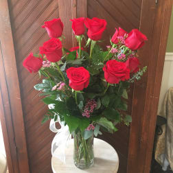 Tall vase of red roses with pink filler flowers and a white ribbon