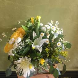 Yellow and white mixed bouquet in a glass vase with a wooden crate
