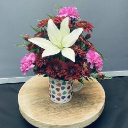 Bouquet of red and pink flowers in a heart-pattern mug