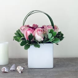 Pink roses in a white square container with a green handle