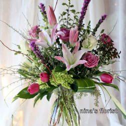 Pink lilies and roses arranged in a clear glass vase