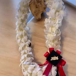 White flower lei with a red ribbon and 2024 charm