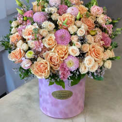 Large pastel bouquet of roses and pink blooms in a lavender hat box