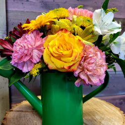 Cheerful mixed bouquet of yellow rose, pink carnations and white lilies in a green watering can
