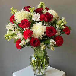 Bouquet of red roses, white chrysanthemums, and white alstroemeria in a glass vase