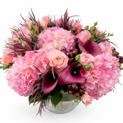 Pink floral arrangement with roses, hydrangeas, and dark calla lilies in a glass vase
